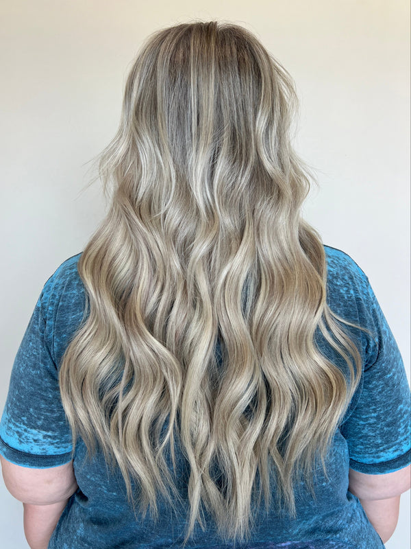 Person holding wavy, blonde hair with a blurred background